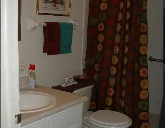 White bathroom sink with vintage tiles, and rolled up organized hand towels in old cottage guest bathroom